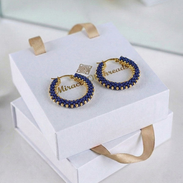 Handmade sapphire blue Miyuki bead hoop earrings with 24K gold plated beads displayed on luxury jewelry box
