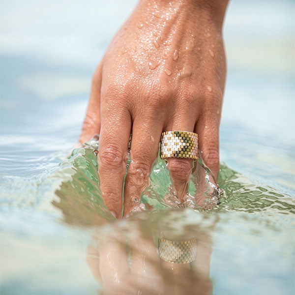 Handmade Miyuki bead ring in ivory and olive green floral geometric pattern with 24K gold plated beads displayed on jewelry box