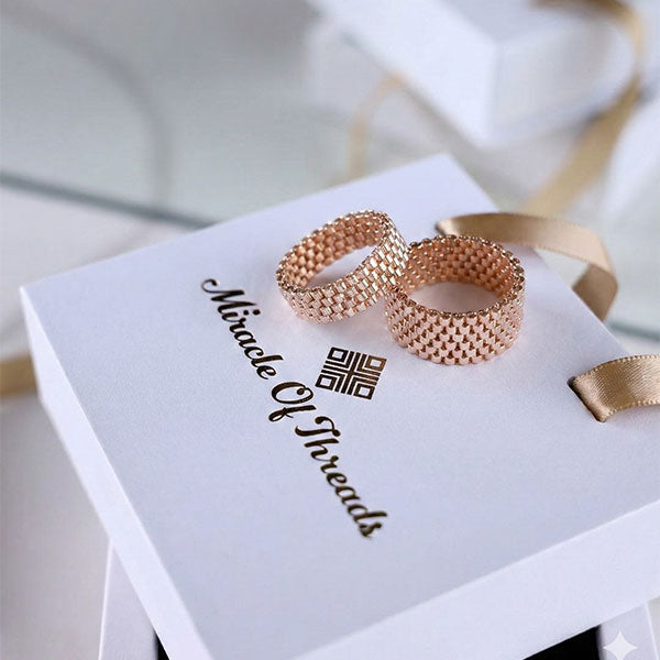 Handmade rose gold Miyuki bead rings on luxury jewelry box