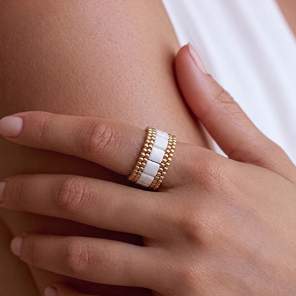 Handmade ivory Tila bead ring with 24K gold plated beads and geometric woven design displayed on jewelry box
