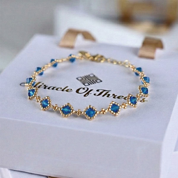 Sapphire blue crystal bracelet with 24K gold plated chain and geometric station design displayed on luxury jewelry box
