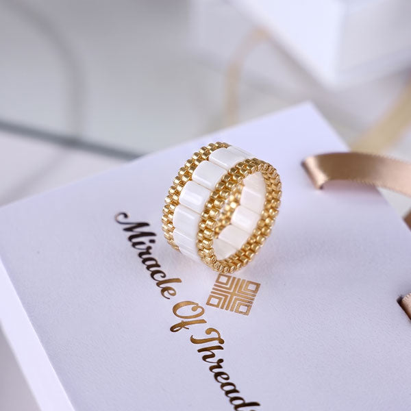 Handmade ivory Tila bead ring with 24K gold plated beads and geometric woven design displayed on jewelry box