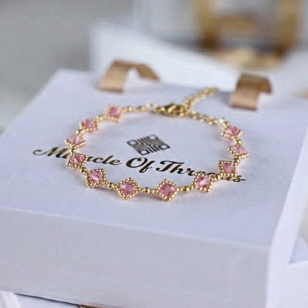 Blush pink crystal bracelet with 24K gold plated chain and halo station design displayed on luxury jewelry box