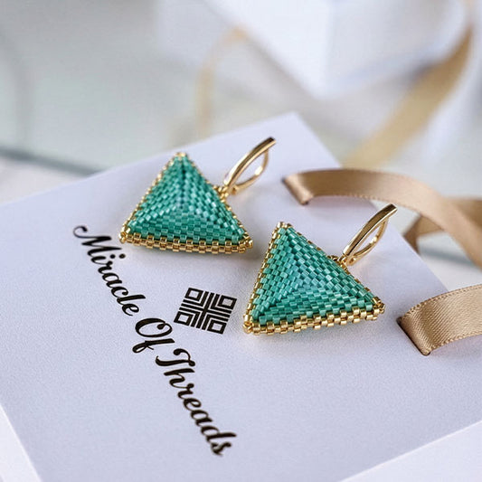 Handmade aqua Miyuki triangle earrings with 24K gold plated hooks displayed on luxury jewelry box
