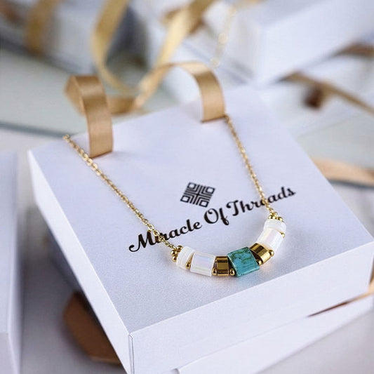 Ivory Tila bead bar necklace with 24K gold plated chain displayed on luxury jewelry box