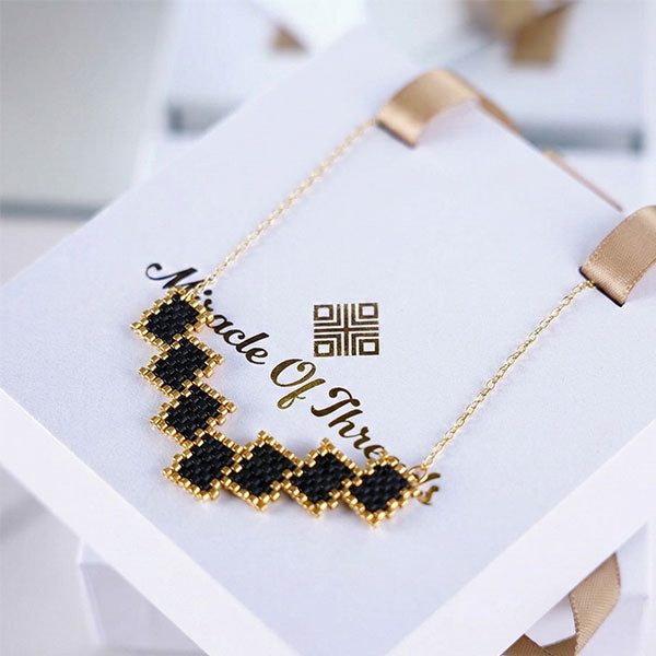 Handmade Miyuki bead necklace with black geometric pattern and 24K gold plated beads on a gold chain