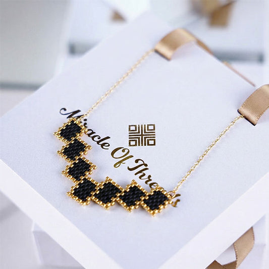 Handmade Miyuki bead necklace with black geometric pattern and 24K gold plated beads on a gold chain