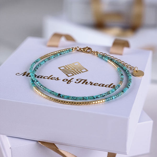 Handmade turquoise Miyuki bead anklet with gold accents and 24K gold plated beads displayed on branded jewelry box