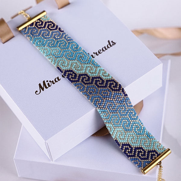 Handmade Miyuki bead bracelet with turquoise and navy geometric wave pattern featuring 24K gold plated beads displayed on jewelry box