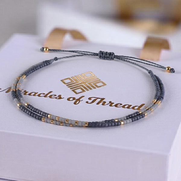 Handmade layered Miyuki bead bracelet in slate grey and gold tones with adjustable cord closure and 24K gold plated beads