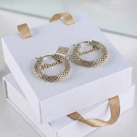 Handmade silver Miyuki bead hoop earrings with woven texture displayed on luxury jewelry box