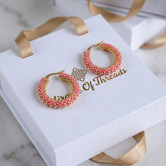 Handmade blush pink Miyuki bead hoop earrings with 24K gold plated beads displayed on luxury jewelry box