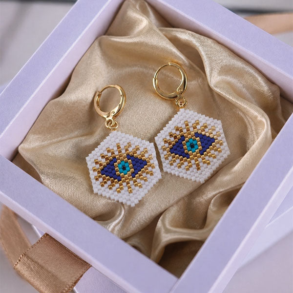 Handmade Miyuki bead evil eye necklace and earrings set with gold star charm and 24K gold plated elements worn on beach