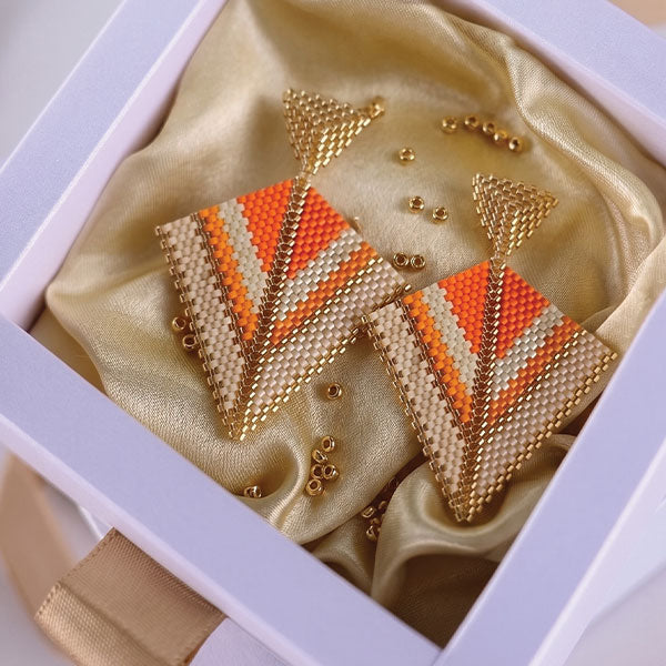 Handmade geometric Miyuki bead earrings in ivory, orange, and gold tones with 24K gold plated elements displayed in gift box