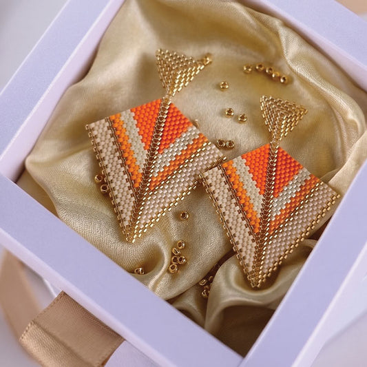 Handmade geometric Miyuki bead earrings in ivory, orange, and gold tones with 24K gold plated elements displayed in gift box