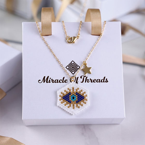 Handmade Miyuki bead evil eye necklace and earrings set with gold star charm and 24K gold plated elements worn on beach