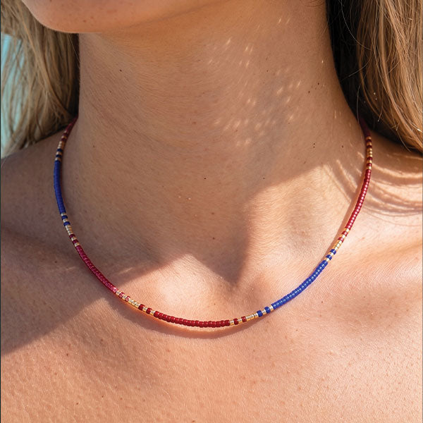 Handmade Miyuki bead necklace in berry pink and blue tones with gold accents and 24K gold plated beads displayed on jewelry box