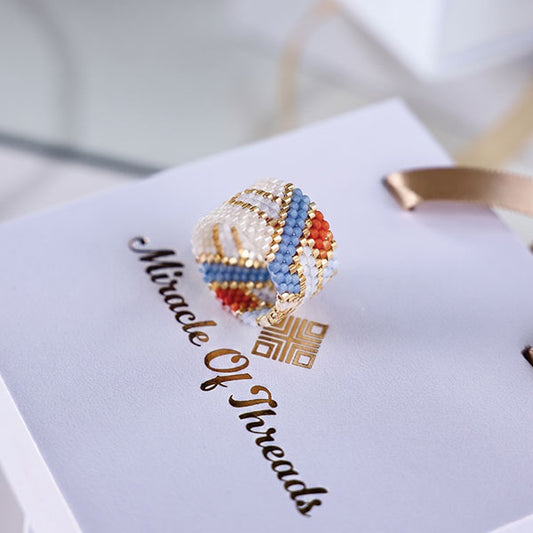 Handmade Miyuki bead ring in ivory, blue, coral, and gold geometric pattern with 24K gold plated beads displayed on jewelry box