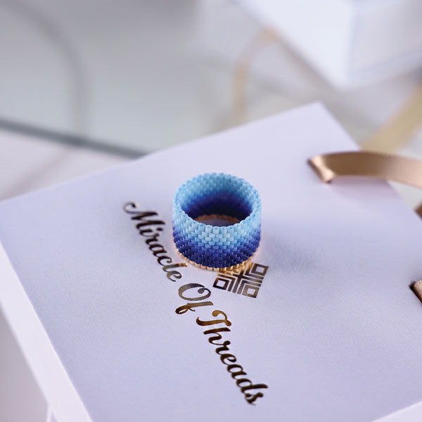 Handmade Miyuki bead ring with blue gradient ombré design displayed on jewelry box