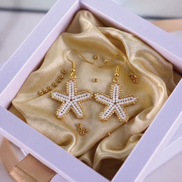 Handmade Miyuki bead starfish necklace and earrings set in ivory and gold tones with 24K gold plated elements worn on beach