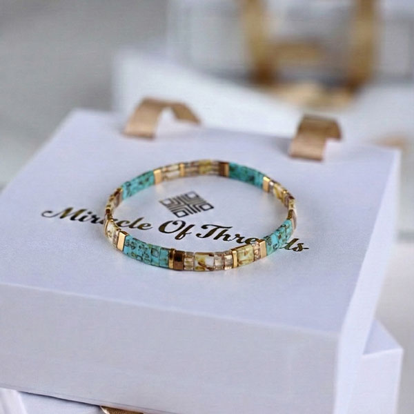 Handmade Miyuki Tila bead bracelet with turquoise tones and 24K gold-plated accents in a flat geometric design