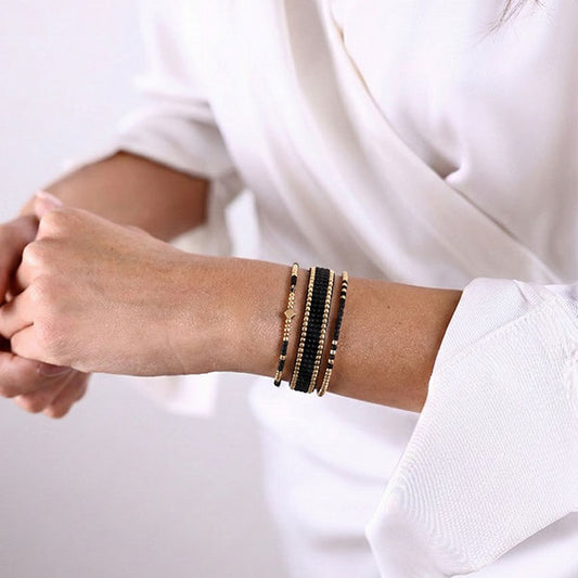 Set of three handmade Miyuki bead bracelets in black and gold tones with 24K gold plated beads worn stacked on wrist