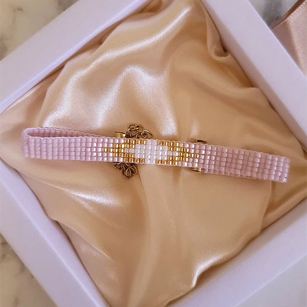 Handmade blush Miyuki bead bracelet with central gold detail and 24K gold plated beads displayed on gift box