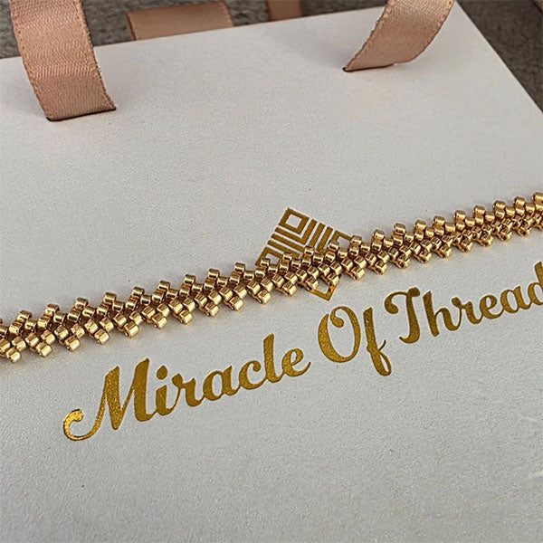 Handmade gold Miyuki bead bracelet with cascading geometric texture and 24K gold plated beads displayed on branded gift box