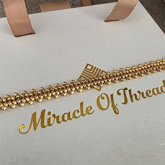 Handmade gold Miyuki bead bracelet with cascading geometric texture and 24K gold plated beads displayed on branded gift box