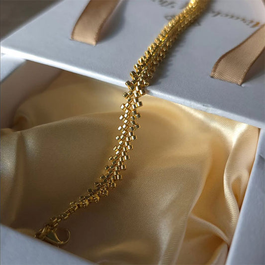 Handmade gold Miyuki bead bracelet with cascading geometric texture and 24K gold plated beads displayed on branded gift box
