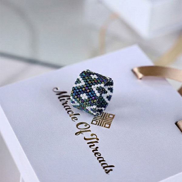 Handmade Miyuki bead ring with geometric mosaic pattern in blue, black, and ivory tones