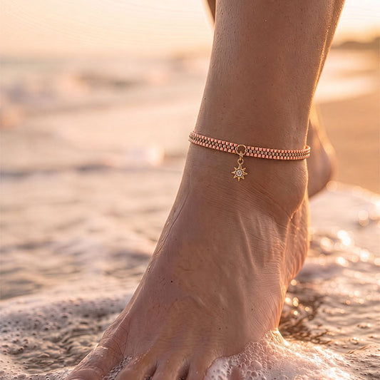 Handmade Miyuki bead anklet in blush and rose tones with 24K gold plated beads and delicate sun charm worn at the beach